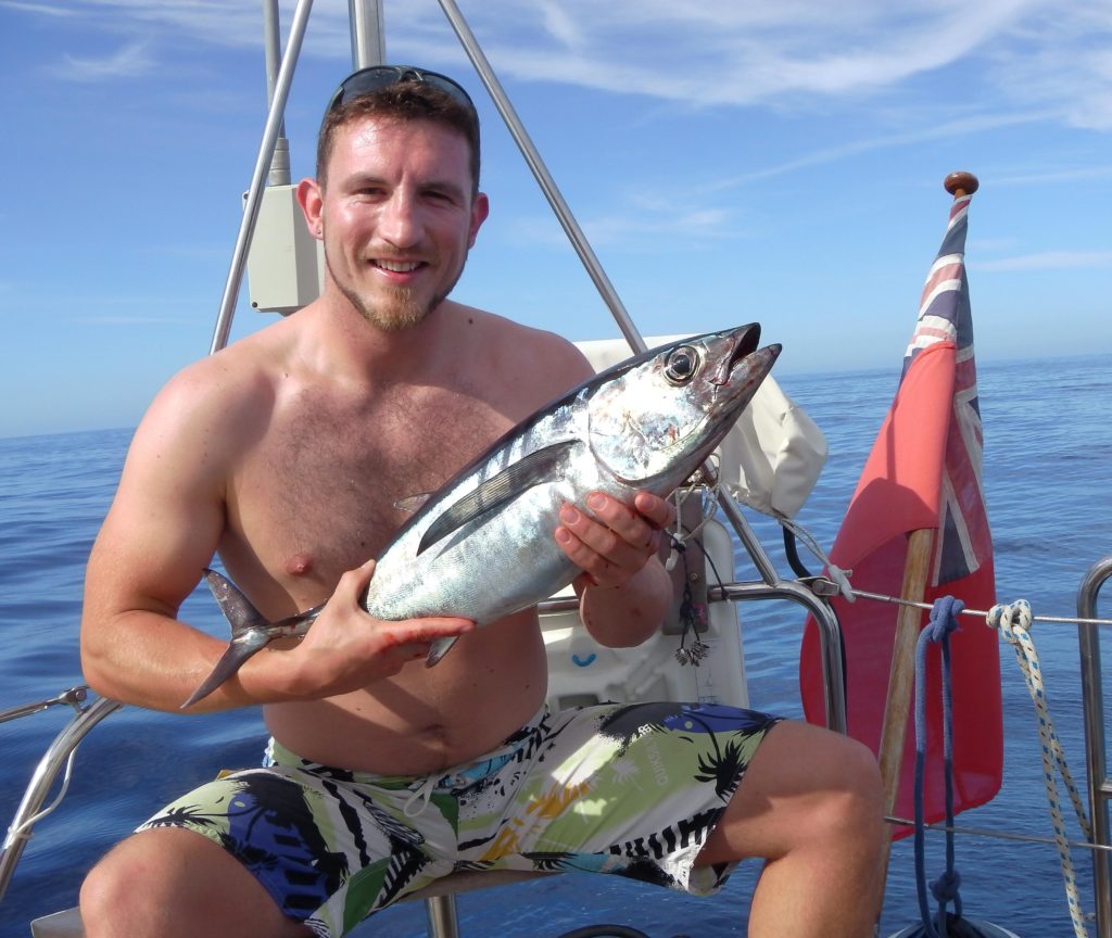 Yacht delivery crew holding a tuna with a smile on his face