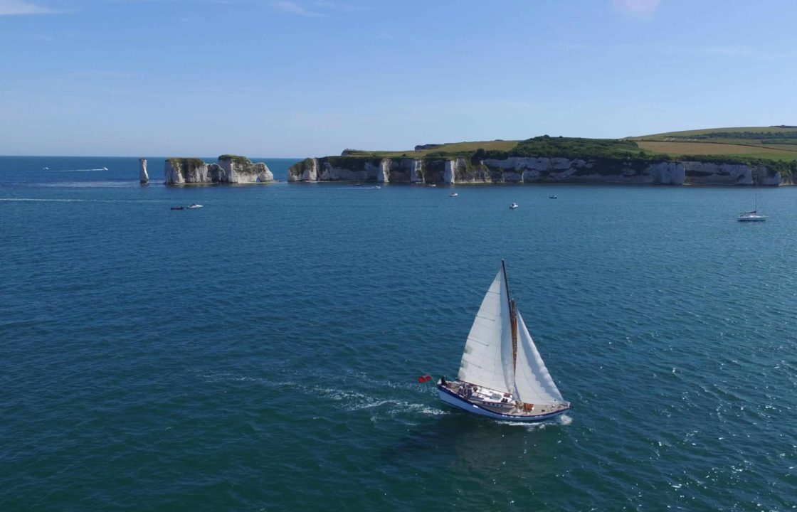 An aerial photo of classic yacht Boleh sailing with the old harry rocks in the background