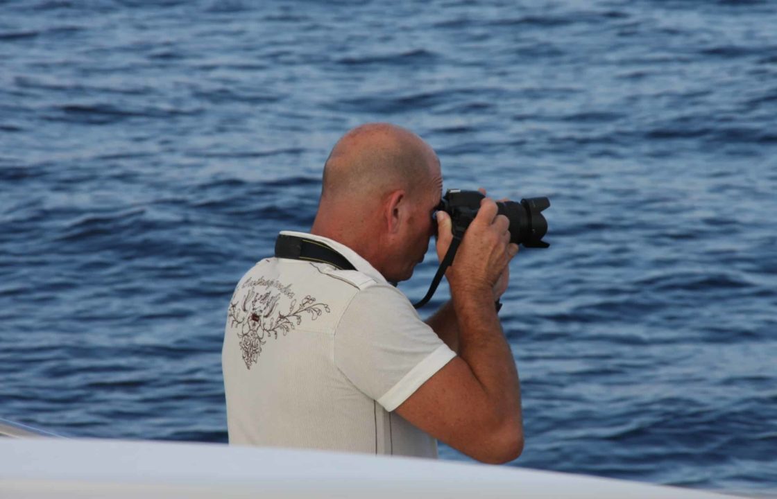 A sailor taking a photograph with an slr camera.