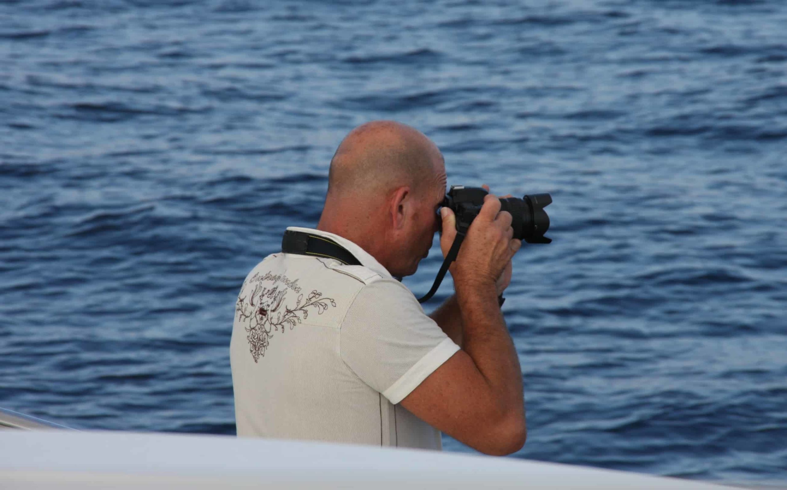A sailor taking a photograph with an slr camera.