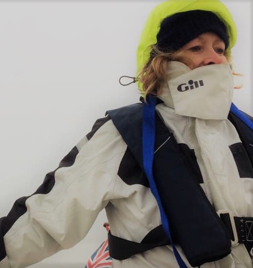 Artist Carolyn Tyrer sailing on her yacht with lifejacket and wet weather gear on.