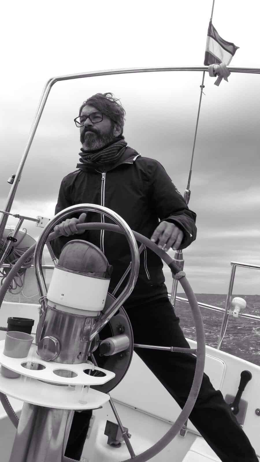 Professional yachtmaster at the helm sailing a yacht on delivery