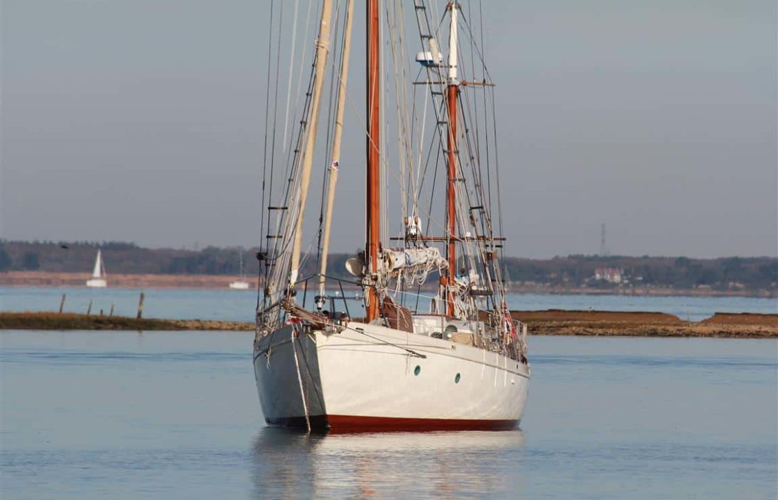 A beautiful white classic yacht with wooden masts at anchor in the Solent.