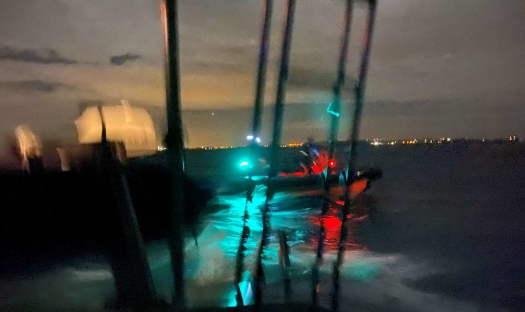 A blurry picture of a police boat approaching us at night.