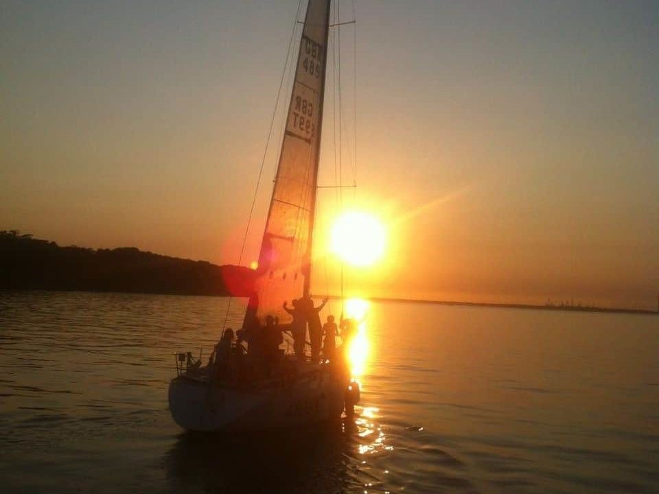 A sailing yacht with the sun setting behind.