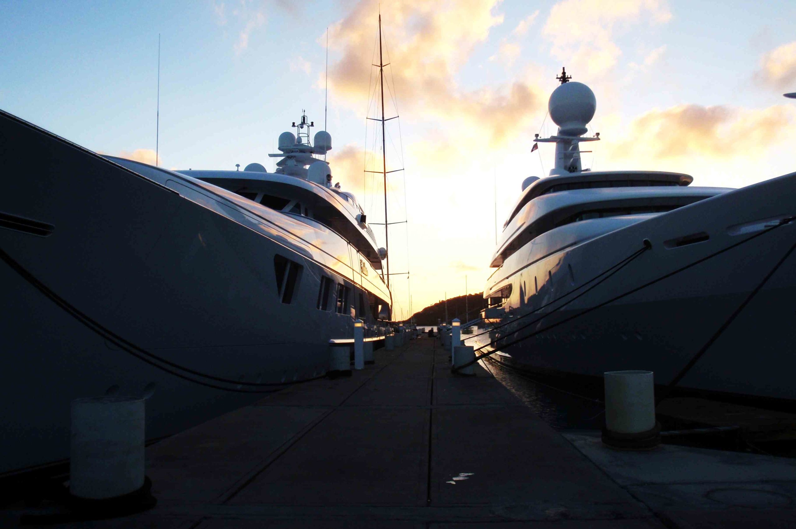 Two superyachts with the sun setting behind
