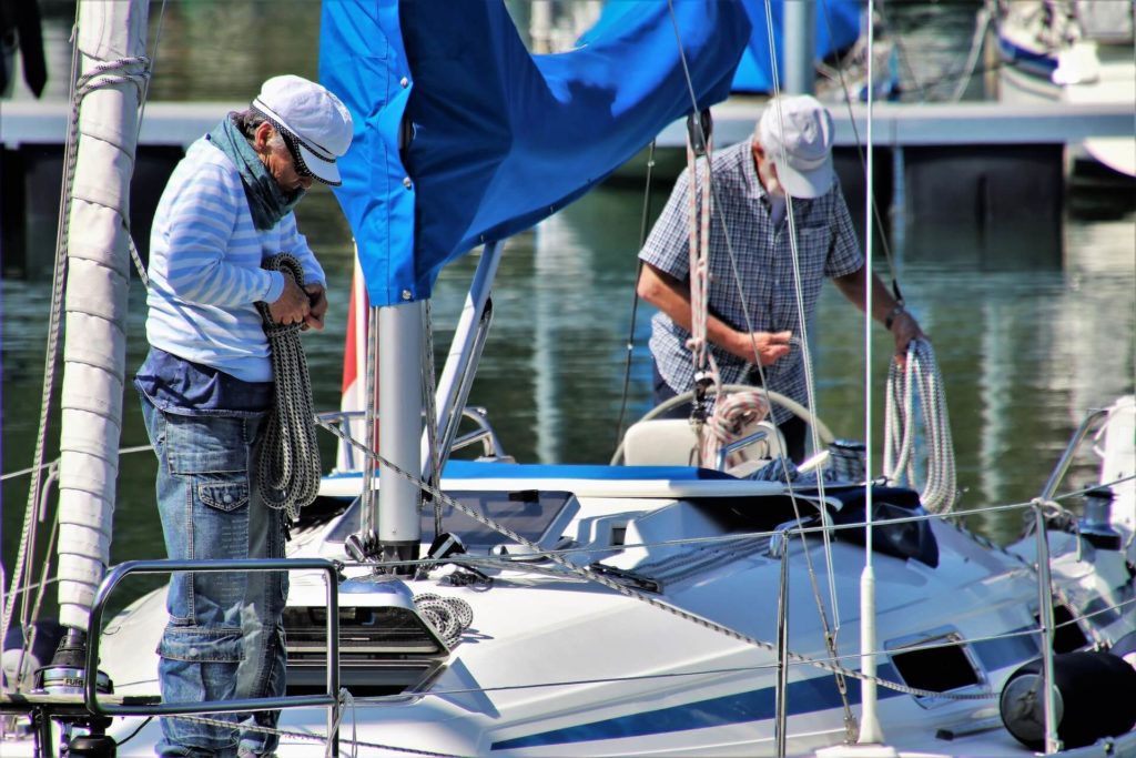 how to prepare your yacht for delivery. Two men coiling lines on the deck of a sailing yacht.