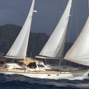 Amel 54 yacht under full sail with mountains in the background